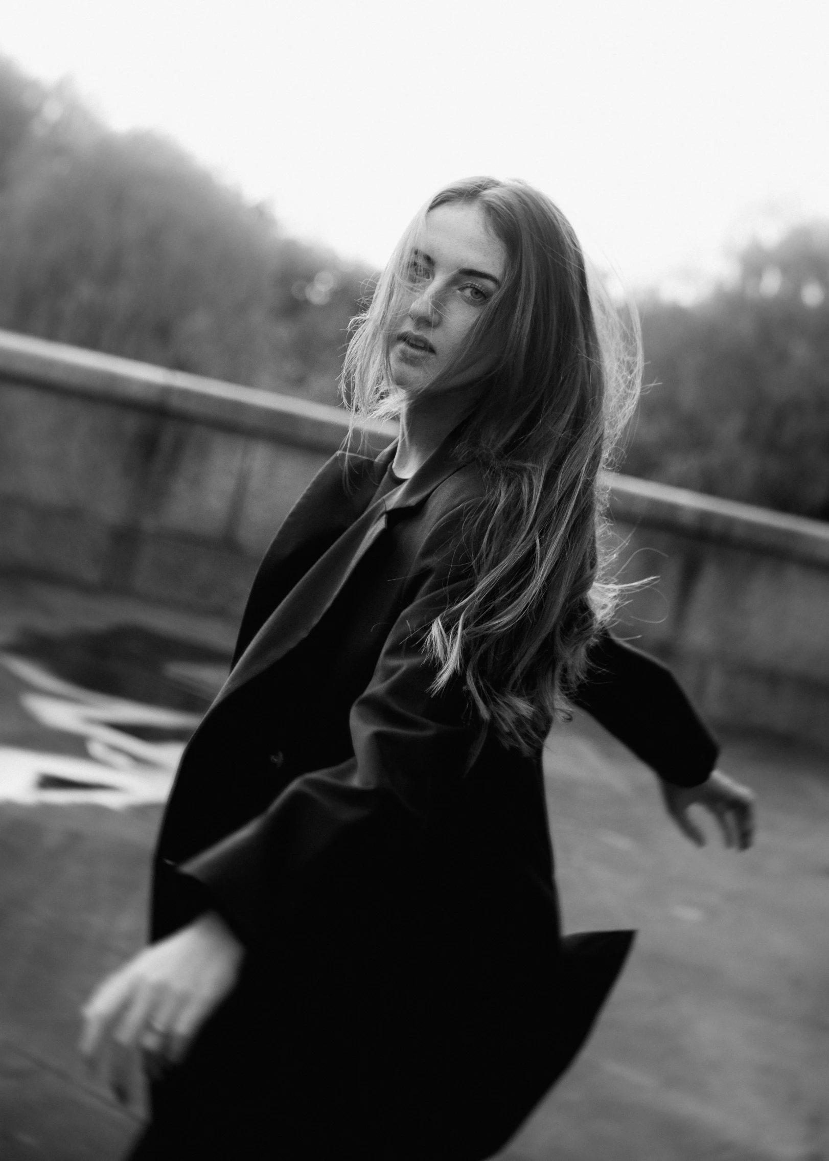 a woman with long hair standing on top of a sidewalk