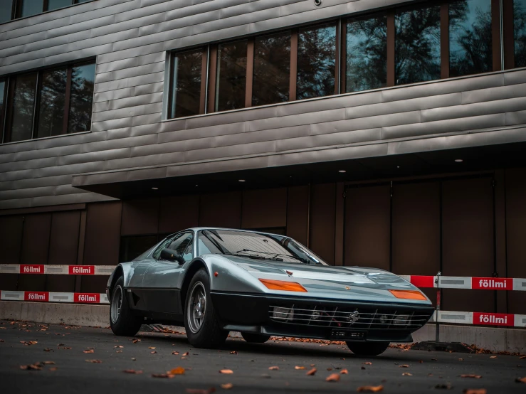 a silver car parked in front of a tall building