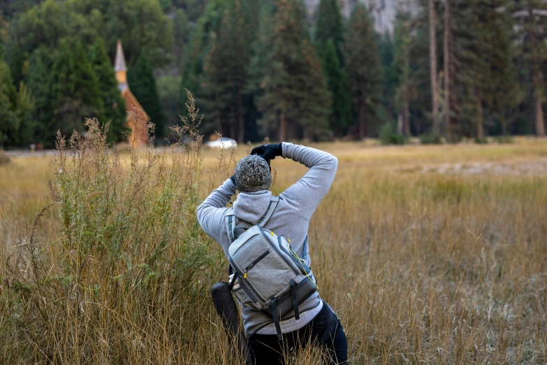 a person standing alone in a field looking at a clock