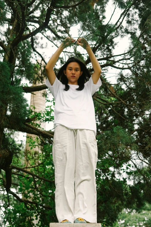 a woman standing on a ledge, in the woods