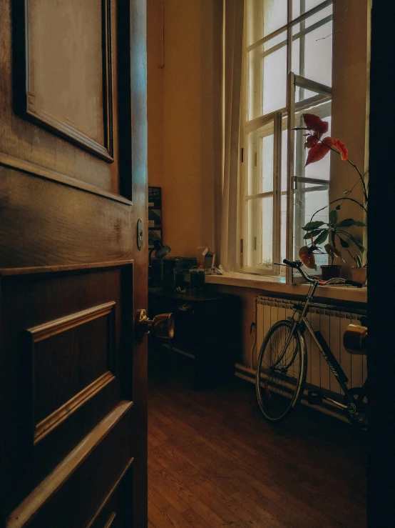 a bicycle sitting in front of a window on a wooden floor