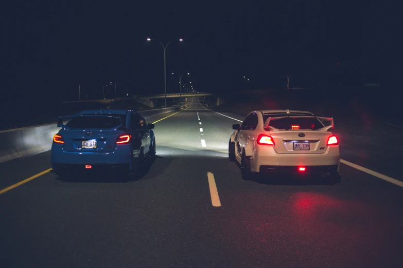 there are two cars driving down the street at night