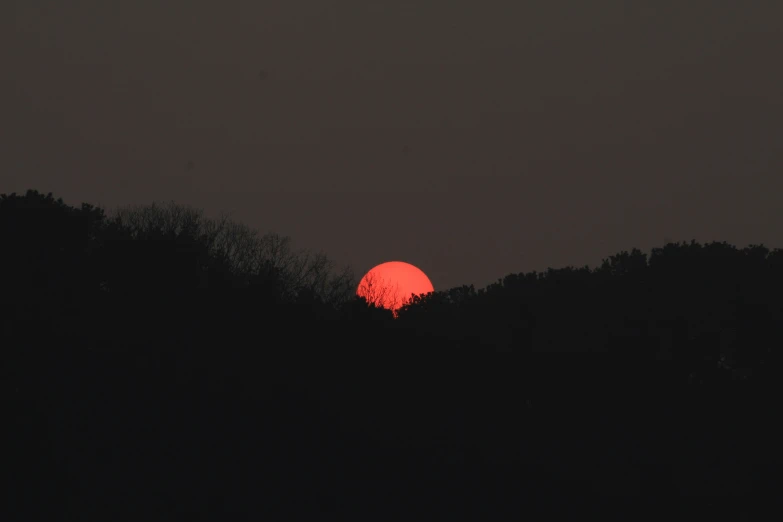 the sun is setting behind a silhouette of trees