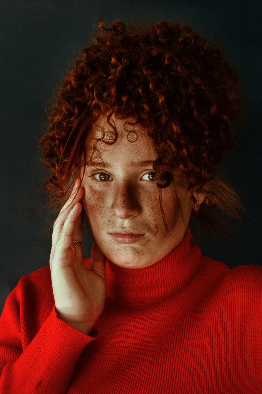 a close up s of a person wearing a red sweater and holding a hand on his head