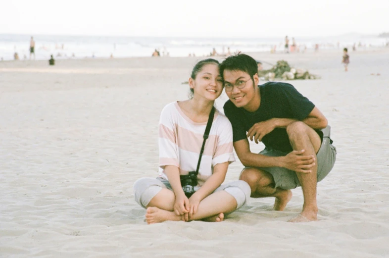 a man and a woman on the beach with their arms around each other