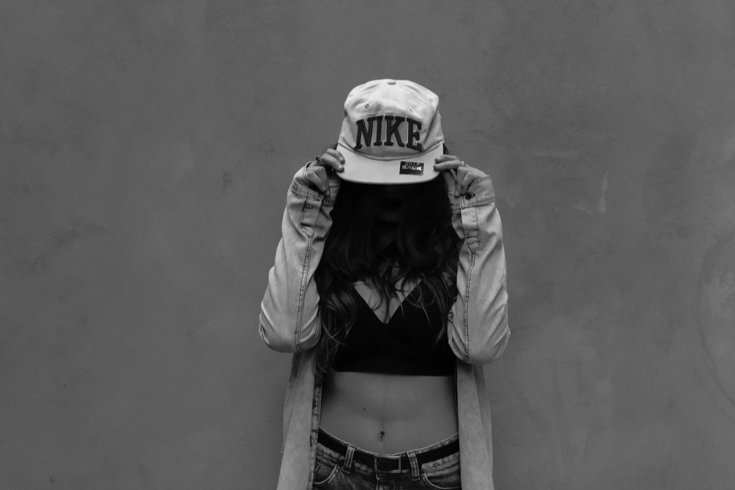 a black and white po of a girl holding a hat over her head