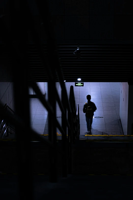 a man is walking down the subway platform at night