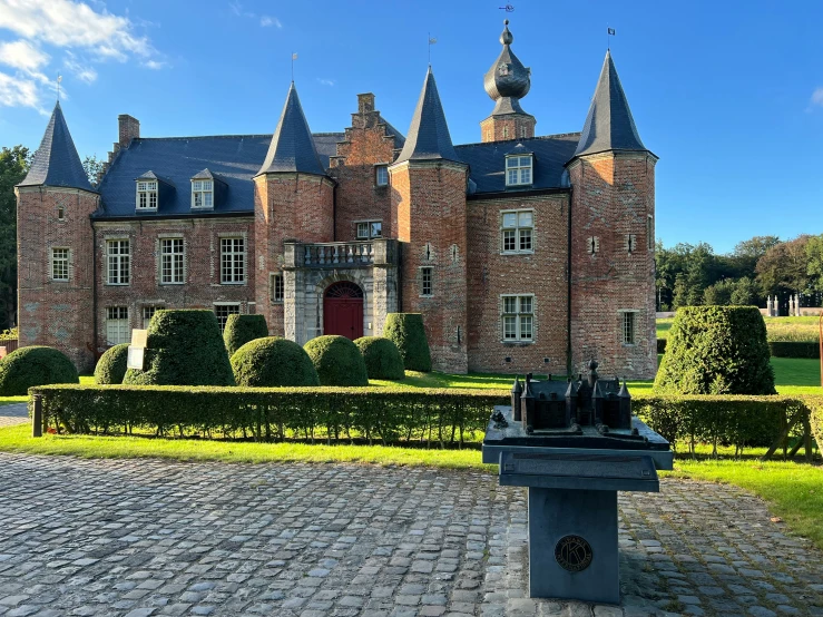 a tall brick building surrounded by hedges and trees