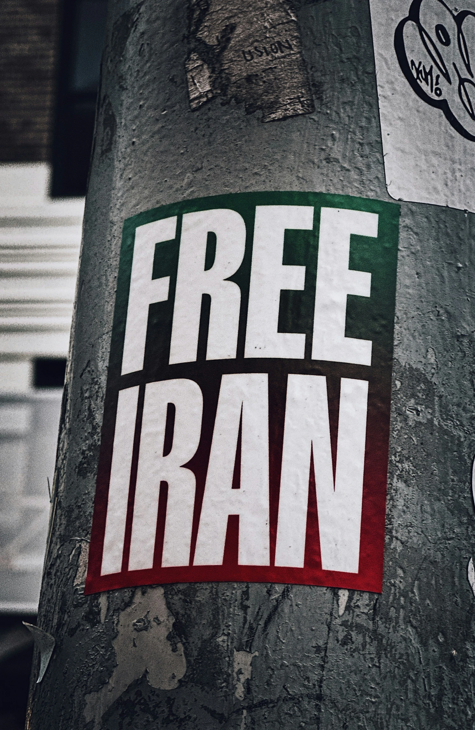 a sticker on a tree has an ad saying free iran