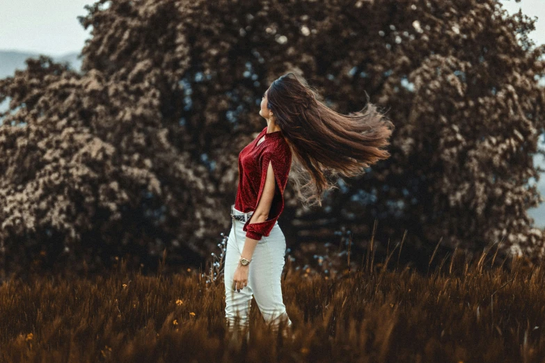 a woman standing in a field with trees in the background