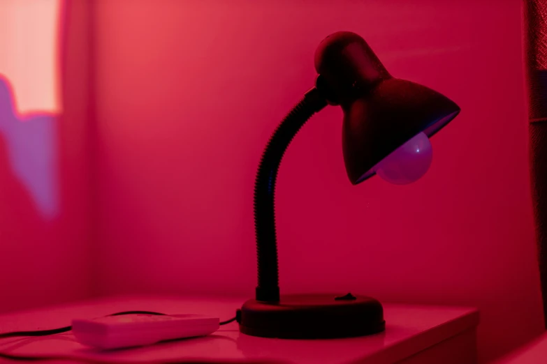 a pink room with a desk lamp and plugged cables on the counter