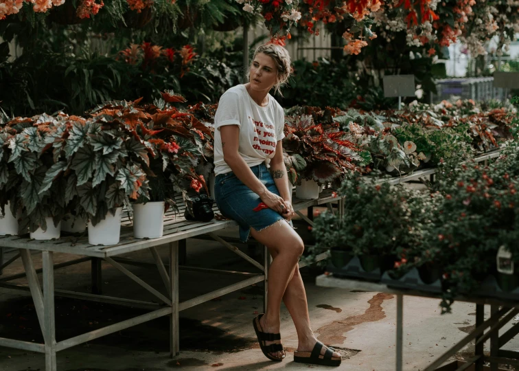 there is a woman that is sitting on a bench in a room full of plants