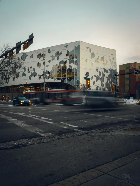 an intersection with car lights, cars driving along it and a building