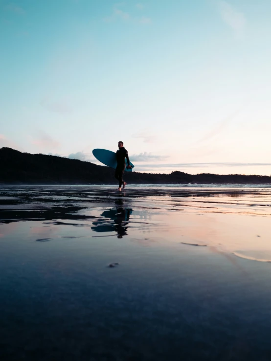 a person is holding a surf board on the beach