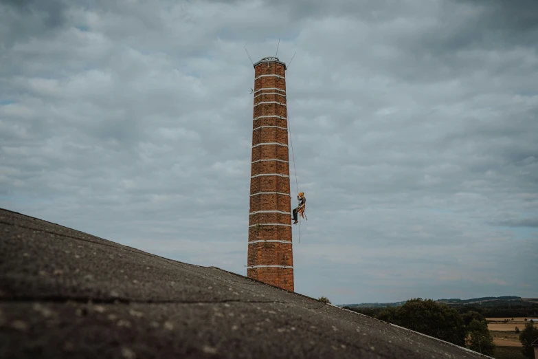 a person hanging on to a tall brick tower