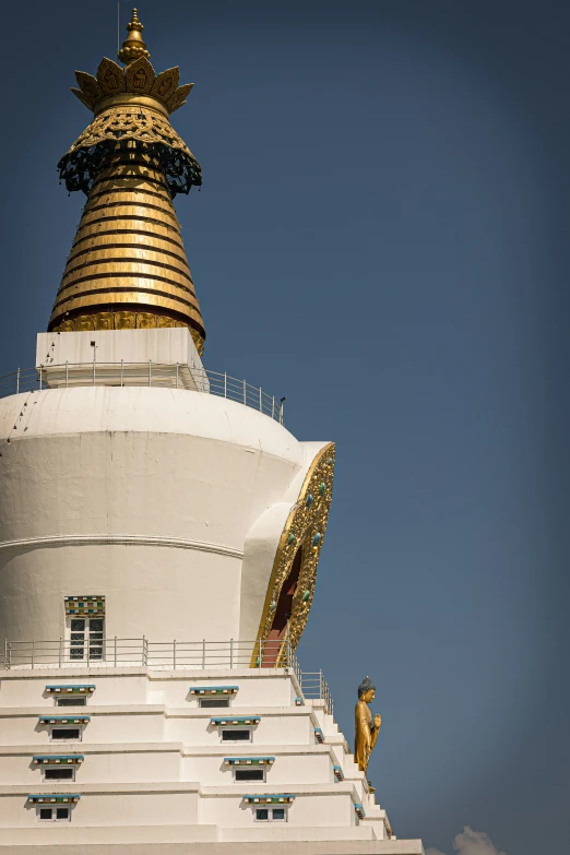 a large white building with golden spire and gold top