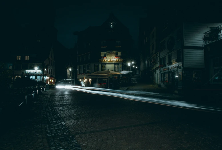 a street at night with buildings and an illuminated clock tower in the background