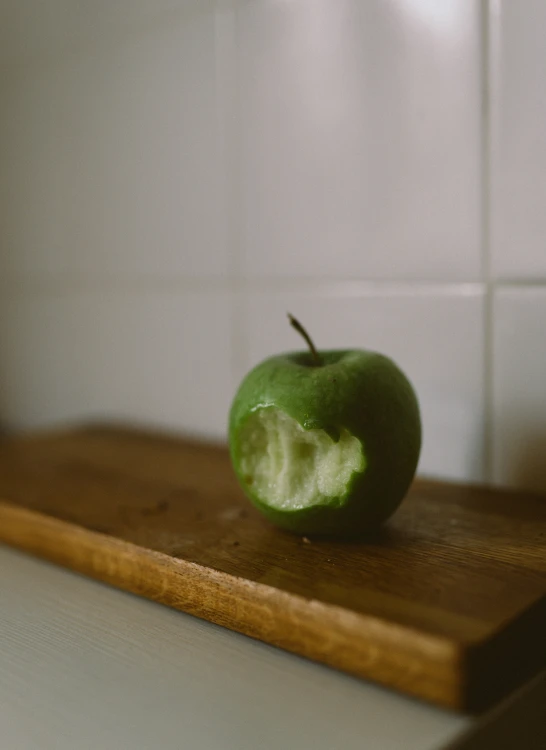 an apple with a bite out of it sitting on a  board