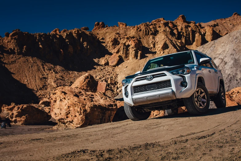 the silver truck is parked on the rocks by itself