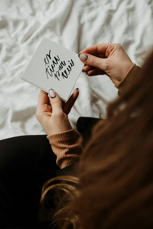 the woman is reading a book with writing on it