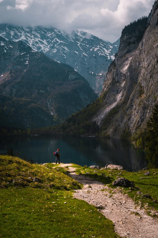 there is a man walking up the path to the lake