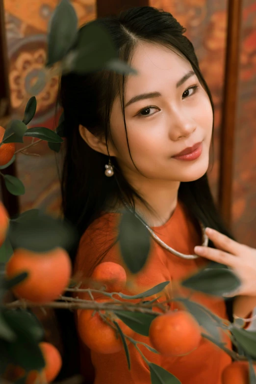 a woman in an orange dress standing near a bunch of tangerines