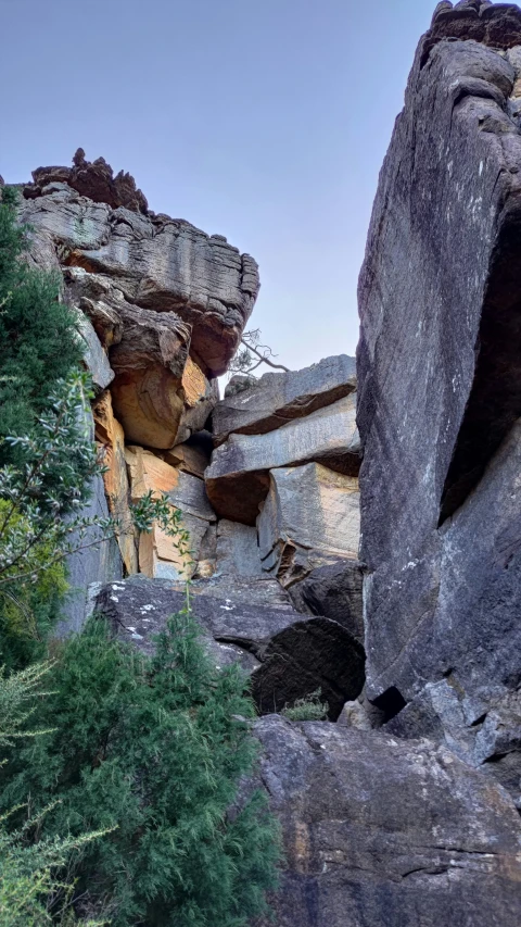 a large cliff covered in tall rocks with trees below