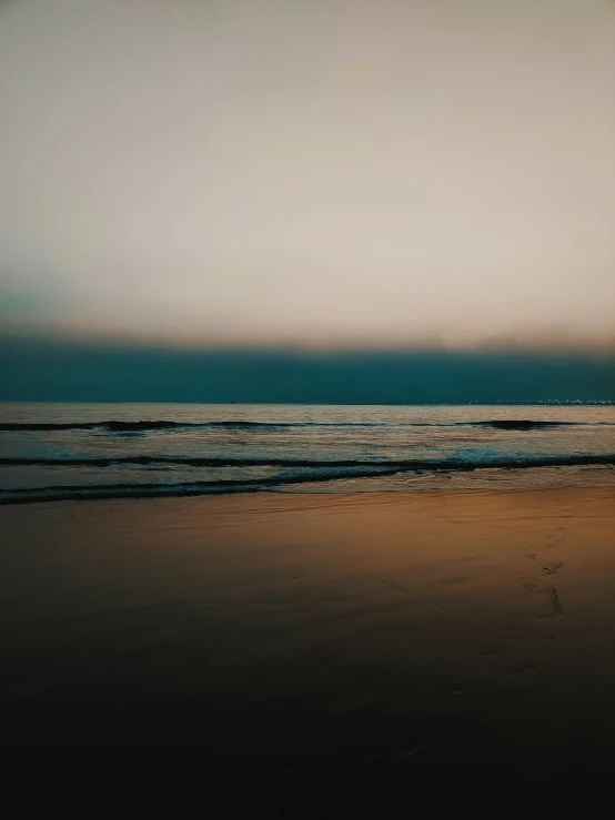 an ocean shore during a cloudy sunset