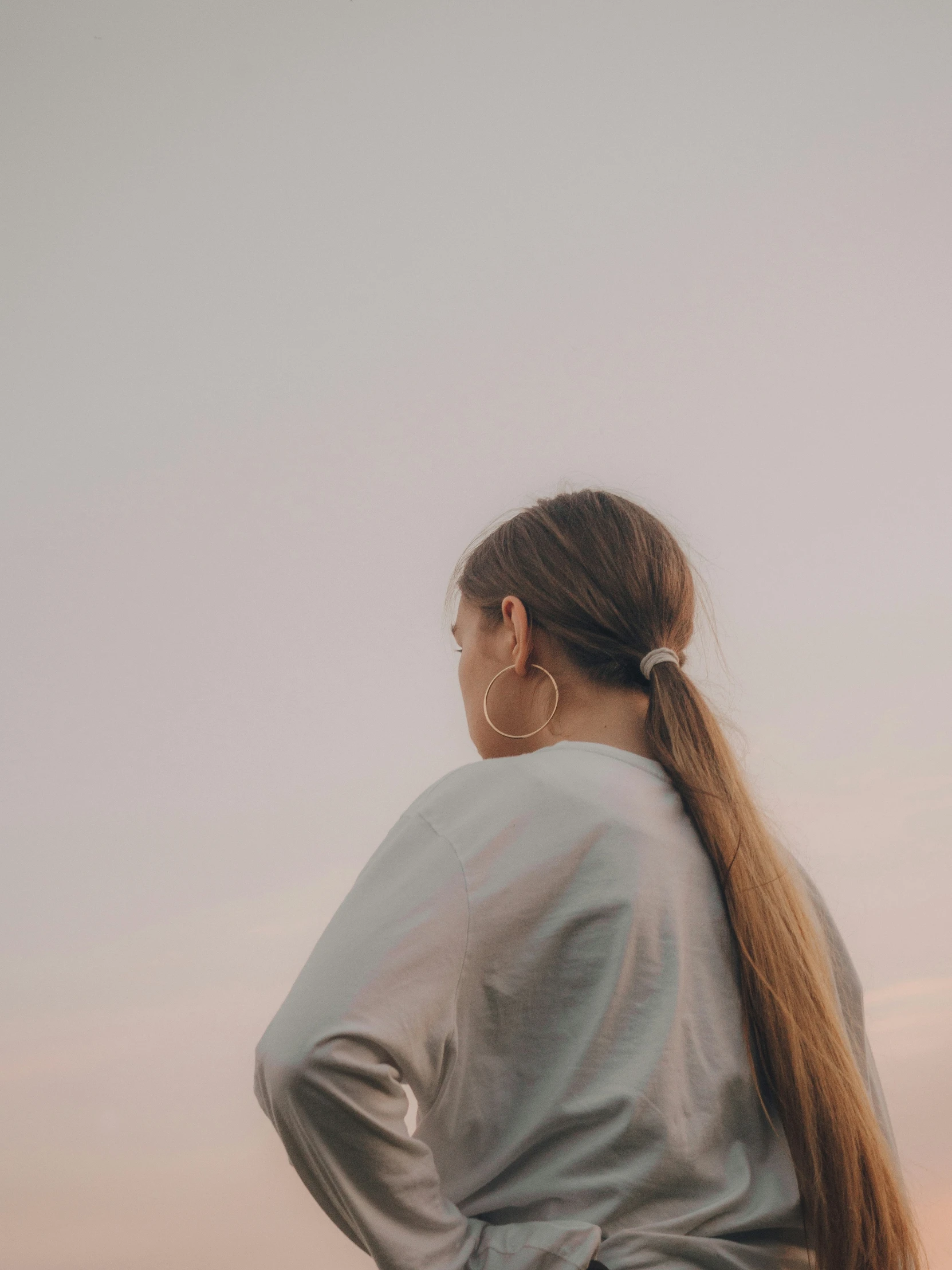 a woman with long hair stands back and looks over her shoulder