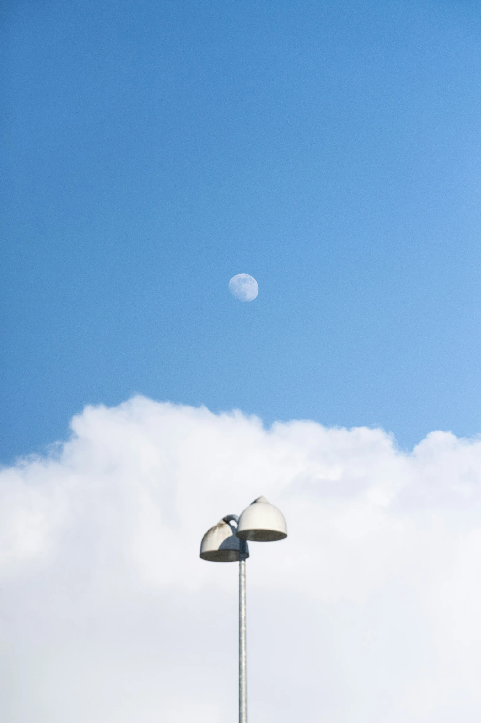 a white lamp post next to a cloud filled sky