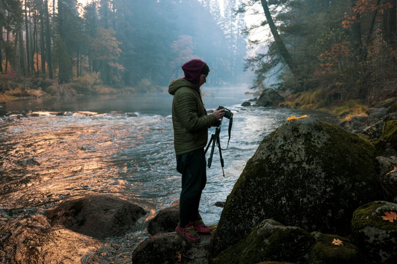 a person is standing on the shore taking pictures of a river