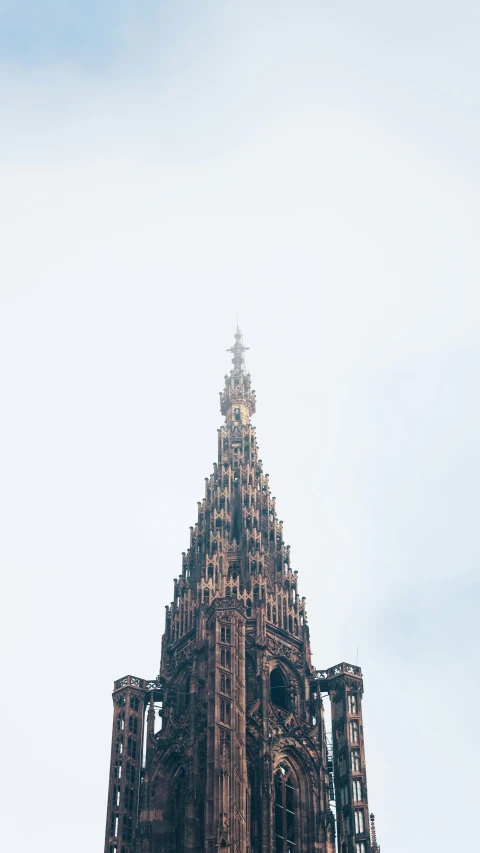 the spire of an ornately designed church against a pale blue sky