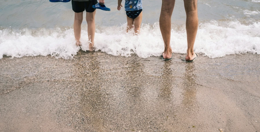 two children standing at the edge of the water