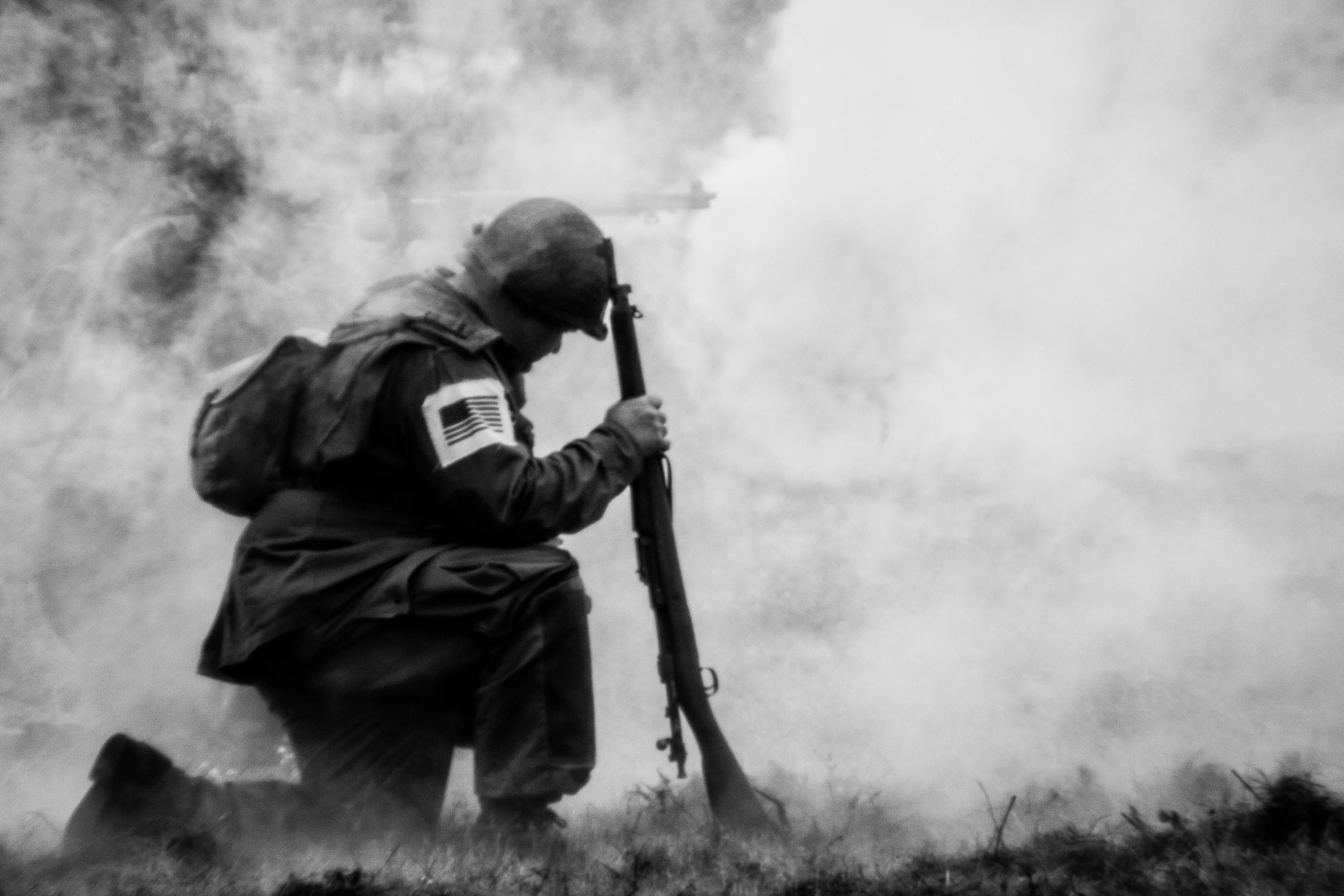 a man with a gun in his hands standing by some smoke