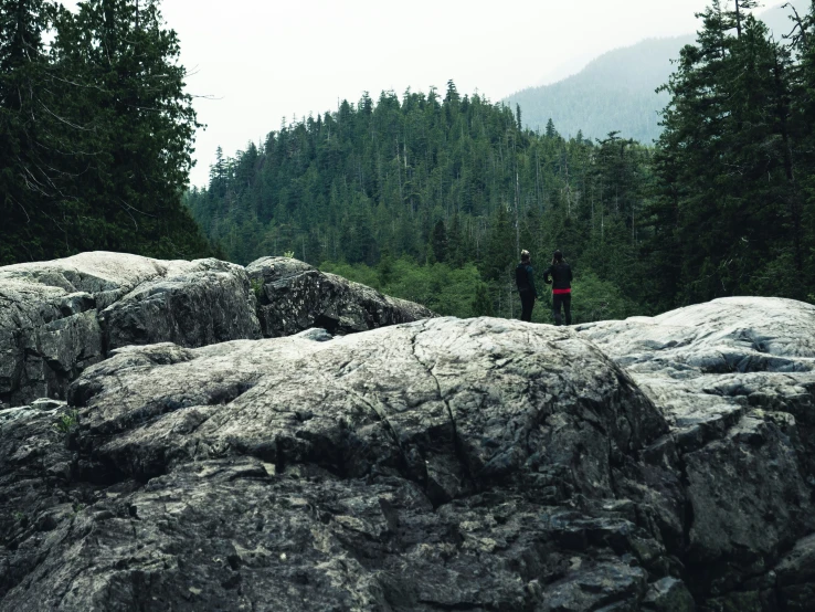 a couple of people standing on the edge of some rocks