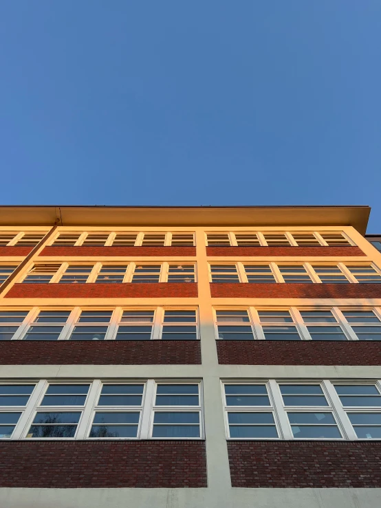 a tall brick building with several windows and a sky in the background