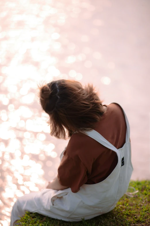 a woman sitting near the water is watching soing