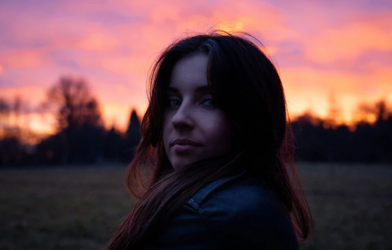 a woman looks at the sunset over her head