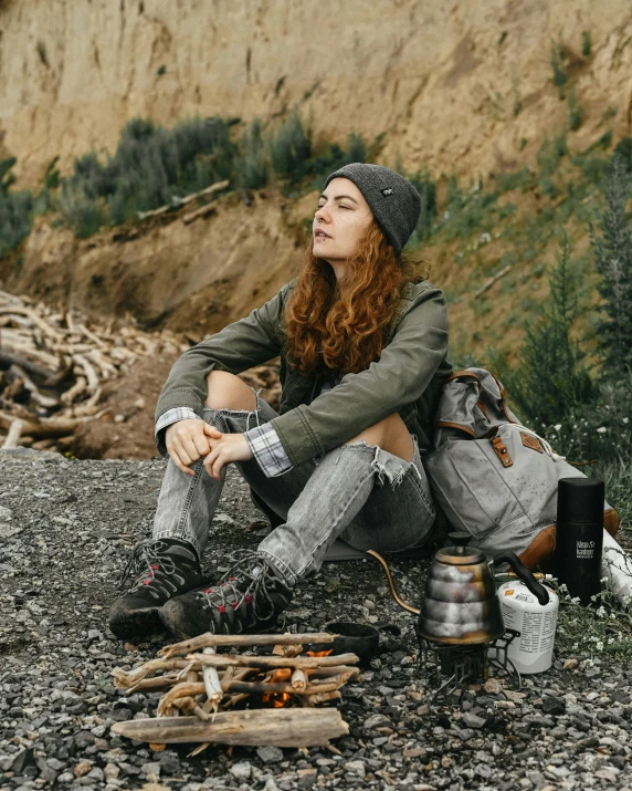 a person sitting on the ground with a backpack and other items