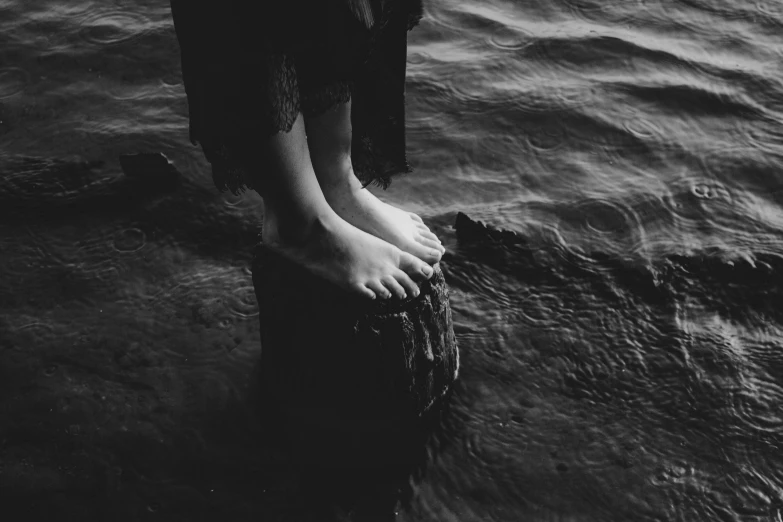 a person with bare feet standing on a wooden pole in water