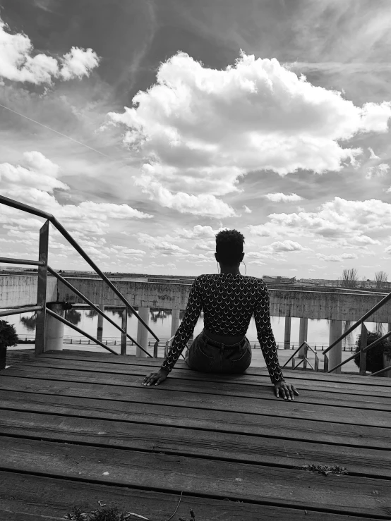 man sitting on boardwalk with an industrial area in the background