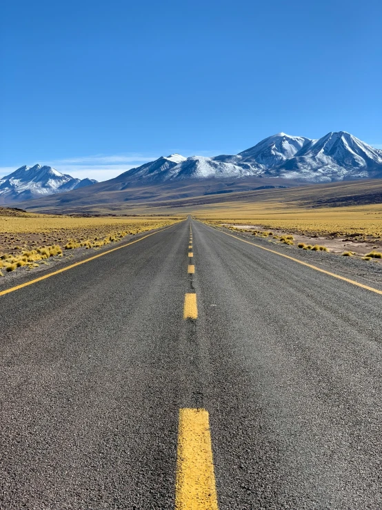 a straight road surrounded by mountains in the distance