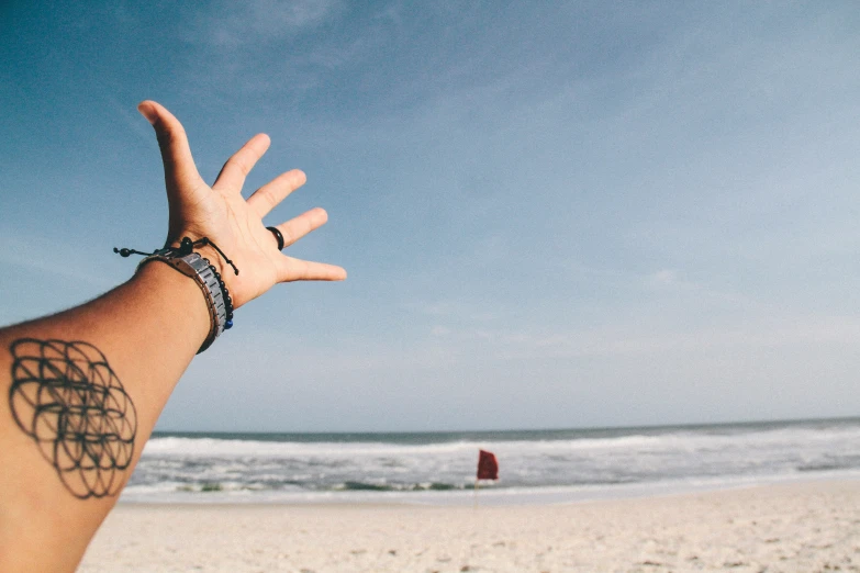 a man with a hand up near the water on a beach