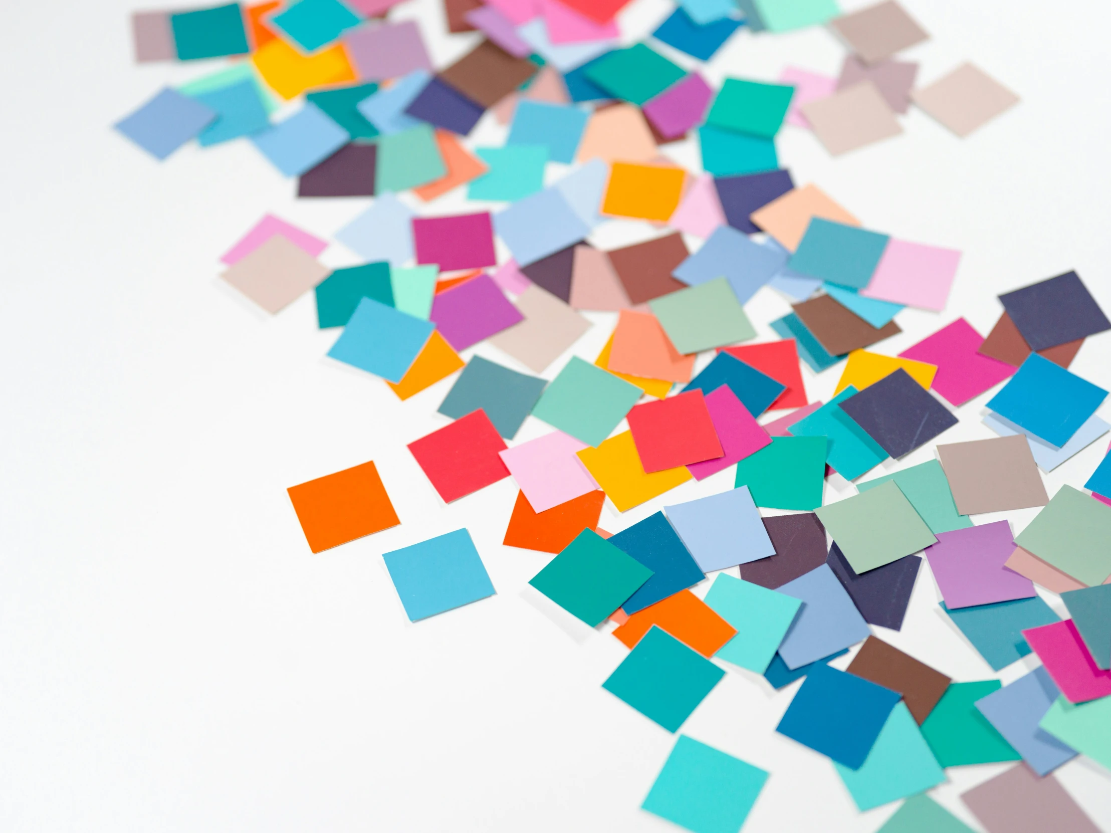 multi - colored geometrically cut squares scattered around a white background