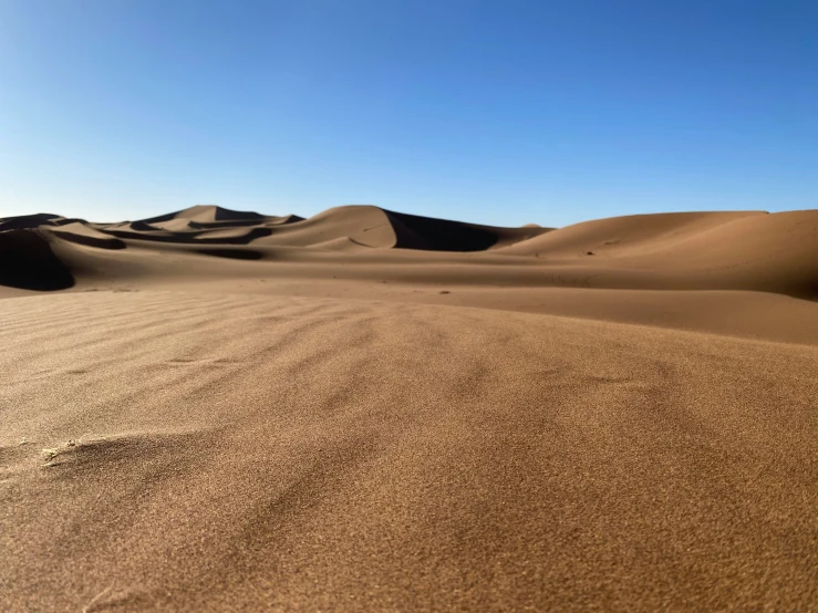 a large brown desert with sand dunes and sun