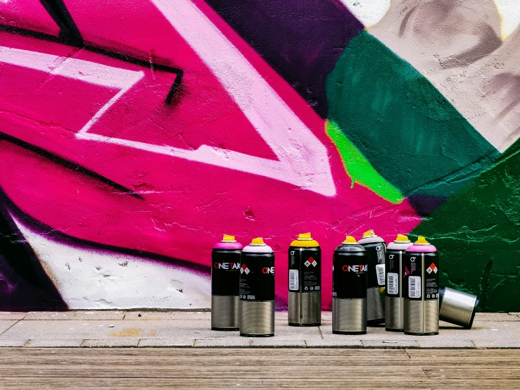 four cans sitting on the ground next to graffiti