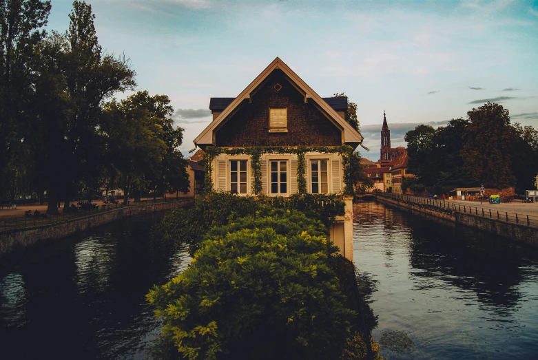 a house next to a body of water near trees