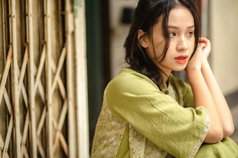 a woman with her hair in the wind sitting against a wall