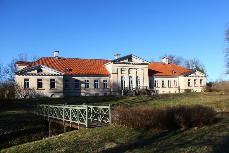 a large mansion with a wooden bridge going across the grass