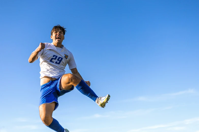 soccer player in blue and white kicking a soccer ball